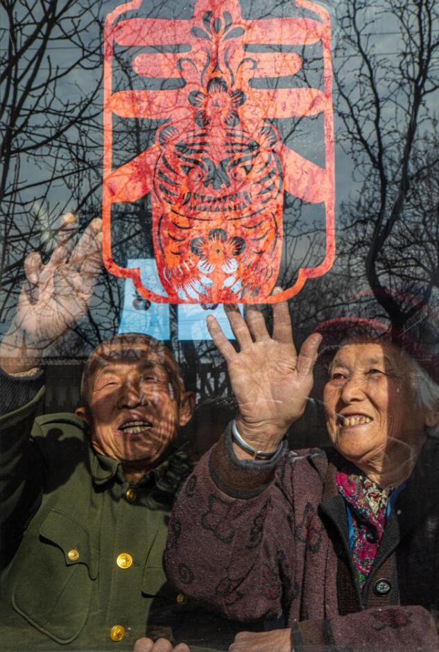 臘月里，霍州市師莊鄉(xiāng)馮南垣村村民師榮光(左)在災后重建的新家里貼窗花。(霍州市委宣傳部供圖)