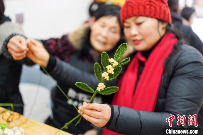馮燕霞指導(dǎo)姐妹們鉤織月桂葉片。　古良駒 攝
