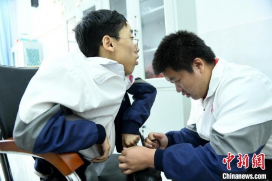 江西省南康中學(xué)北校區(qū)的高三學(xué)生朱金祥(右)正在給鐘華強(qiáng)(左)系好鞋帶。 卓忠偉 攝