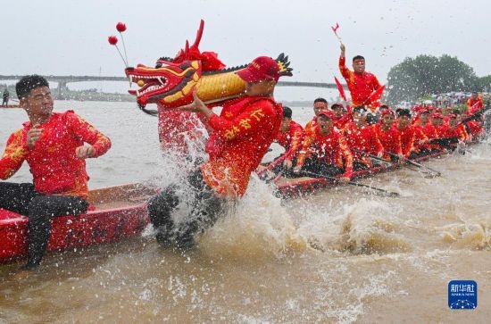 6月22日，在湖南省岳陽市湘陰縣湘江臨資口水域，參加龍舟賽的隊(duì)員接“龍頭”下水。