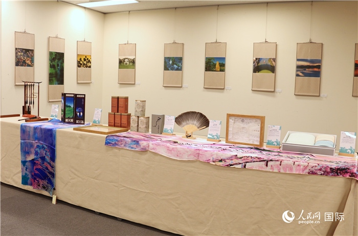 現(xiàn)場展出的馮學(xué)敏攝影作品與湖州市特色工藝品。（人民網(wǎng) 許可攝）