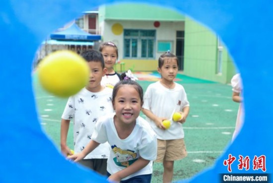 在肥西縣山南鎮(zhèn)中心幼兒園，孩子們在玩布洞投球游戲。陳家樂 攝