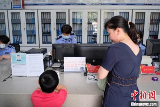 圖為一名家長正在辦證窗口前為孩子申領居民身份證。劉俊聰 攝