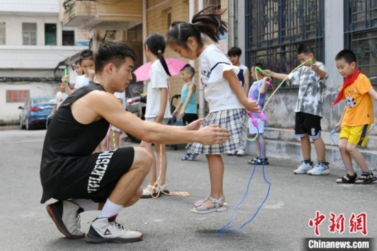 圖為大學(xué)生志愿者在教孩子們學(xué)跳繩。廖光福 攝