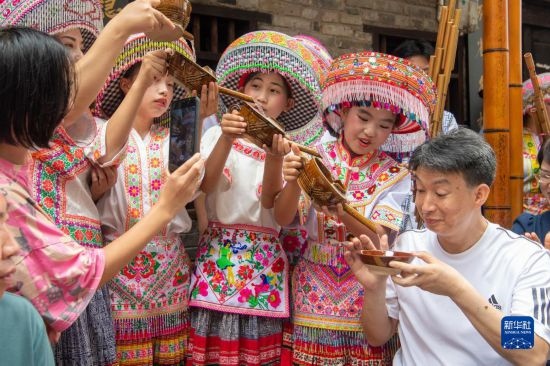 7月29日，在重慶市綦江區(qū)安穩(wěn)鎮(zhèn)，當(dāng)?shù)鼐用裨凇懊缂曳蚬?jié)”上用傳統(tǒng)習(xí)俗向游客表達(dá)祝福。新華社記者 唐奕 攝