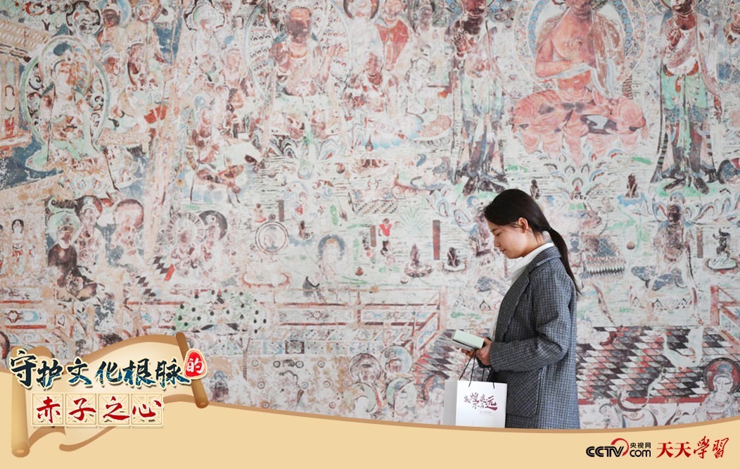 2023年4月25日，敦煌研究院文物數(shù)字化保護(hù)團(tuán)隊(duì)創(chuàng)意營(yíng)銷人員廖雪婷從一幅高保真復(fù)制壁畫前走過。