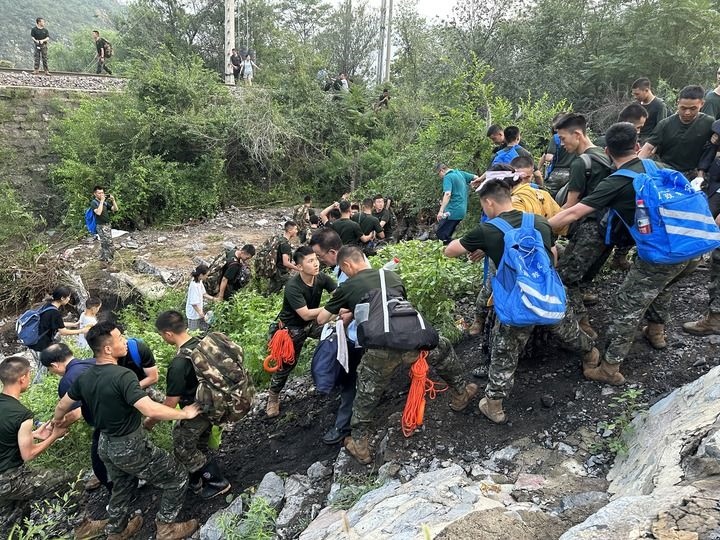 8月2日，Z180次受困列車的旅客在武警北京總隊(duì)機(jī)動第三支隊(duì)官兵的幫助下徒步前往轉(zhuǎn)運(yùn)客車（手機(jī)照片）。新華社記者 王艷剛 攝