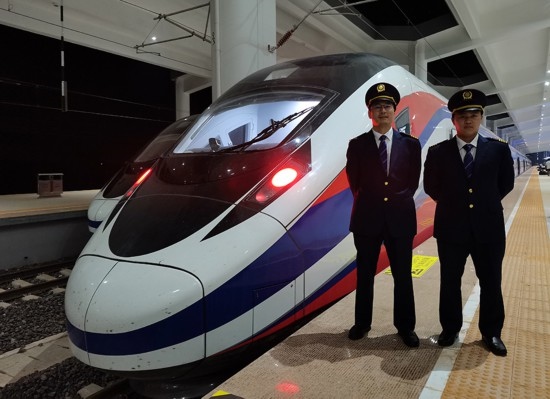 劉銀能（右一）與中國師父鄔俊鴻在動車組前合影。受訪者供圖