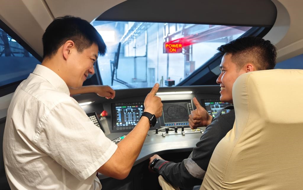 8月25日，在印度尼西亞萬隆的雅萬高鐵德卡魯爾動車所內，中國師傅穆振（左）在向印尼火車司機塞蒂亞萬講解動車組出庫前的上電作業(yè)。