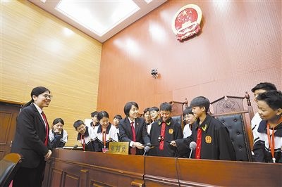 圖③：同學(xué)們穿法袍、敲法槌，爭做“小法官”。