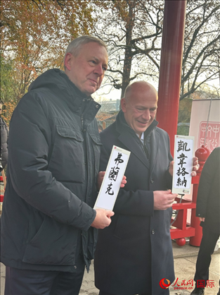 柏林市長韋格納（右）、動(dòng)物園監(jiān)事會(huì)主席布魯克曼（左）手持中國文化中心工作人員現(xiàn)場手書的中文名字。人民網(wǎng)記者 徐馨攝