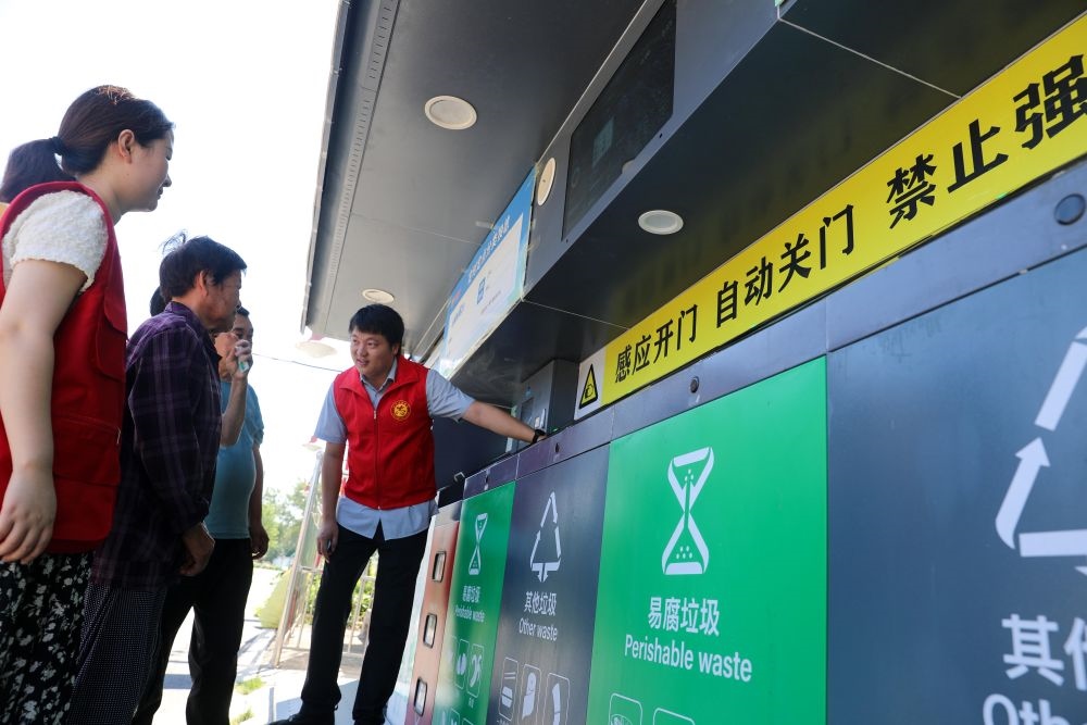 在安徽省合肥市長豐縣莊墓鎮(zhèn)棗林社區(qū)，志愿者指導(dǎo)居民使用智能垃圾分類回收設(shè)備（2023年9月1日攝）。新華社記者 曹力 攝