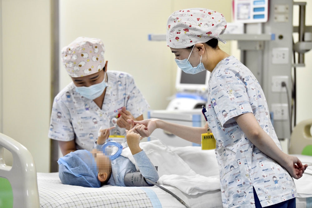 在山東省棗莊市婦幼保健院兒童ICU病房，醫(yī)護人員為完成靶向治療藥物諾西那生鈉的4歲脊髓性肌萎縮癥患兒加油鼓勁（2022年1月1日攝）。諾西那生鈉注射液是我國首個獲批治療脊髓性肌萎縮癥的進口藥物，2019年進入中國市場時，每針價格近70萬元。在2021年國家醫(yī)保目錄藥品談判中，以3.3萬元每針的價格進入新版醫(yī)保藥品目錄。新華社記者 郭緒雷 攝