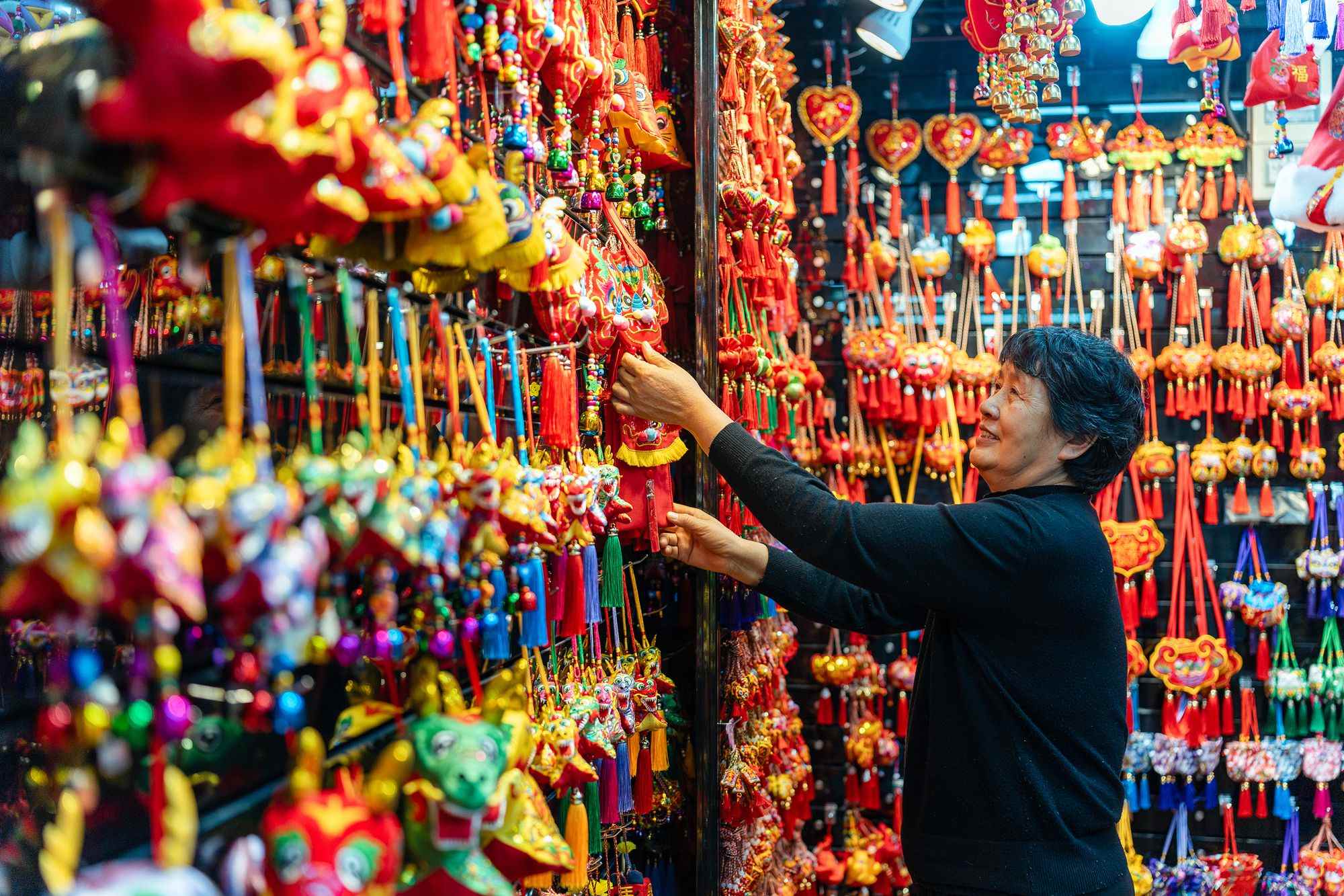 2023年12月11日，金華義烏國(guó)際商貿(mào)城，龍年喜慶用品掛滿(mǎn)攤位，顧客正在挑選中。