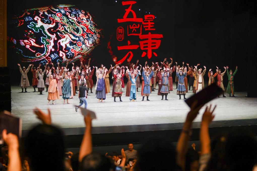 2023年7月31日，新疆和田地區(qū)新玉歌舞團在烏魯木齊京劇院演出舞劇《五星出東方》后和觀眾互相揮手致意。這場演出是第六屆中國新疆國際民族舞蹈節(jié)的參演劇目之一，曾榮獲國家“文華獎”等。新華社記者 郝昭 攝