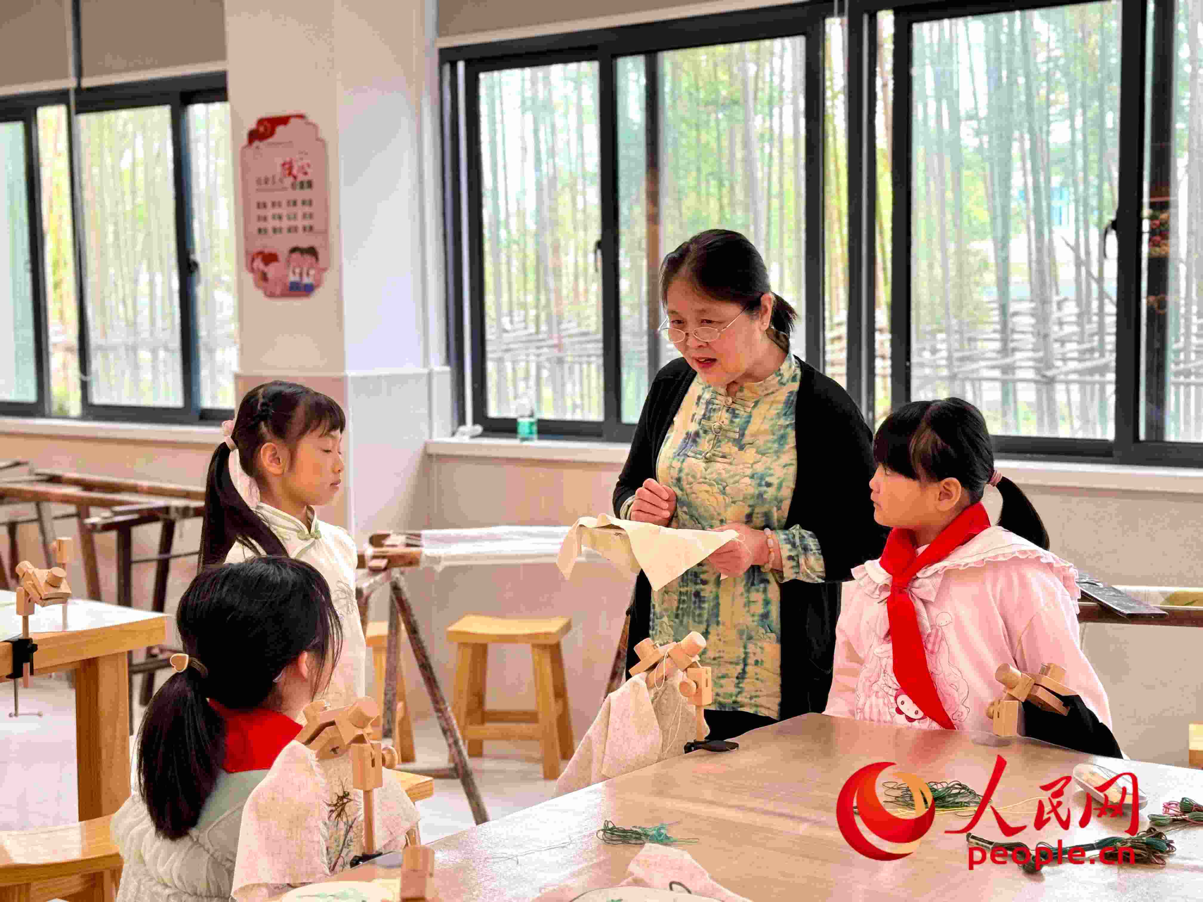 顧建珍（左三）在教孩子們刺繡知識(shí)。人民網(wǎng) 周靜圓攝