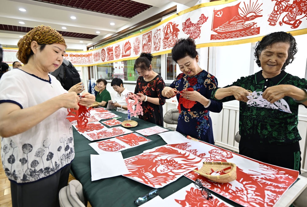 6月19日，長城花園社區(qū)居民在社區(qū)“才藝堂”制作剪紙。