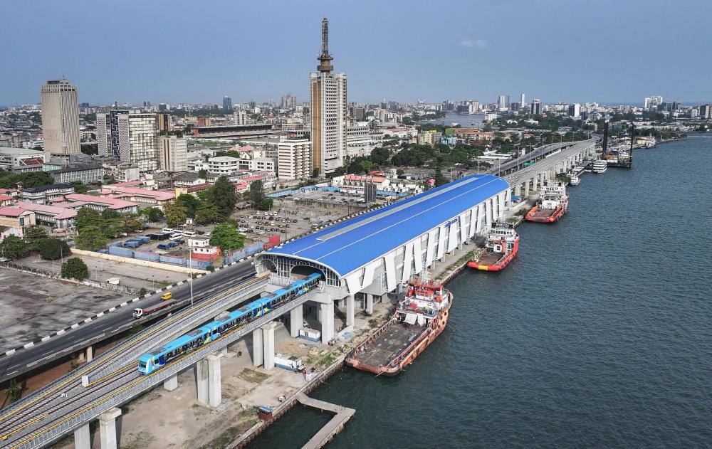 2024年3月2日，在尼日利亞拉各斯，一列輕軌藍線列車駛?cè)氪a頭站（無人機照片）。拉各斯輕軌藍線是西非地區(qū)首條由中國企業(yè)自主設(shè)計、建造、施工、運營的電氣化城市軌道交通項目。新華社記者 韓旭 攝