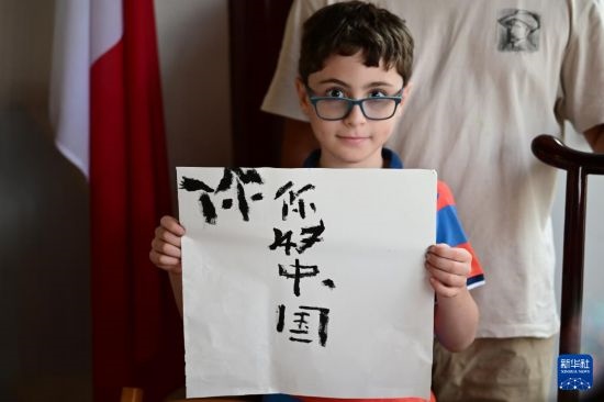 7月4日，在馬耳他桑塔露琪亞市的中國古典園林“靜園”，一名男孩展示他的書法作品。新華社發(fā)（喬納森·博格 攝）