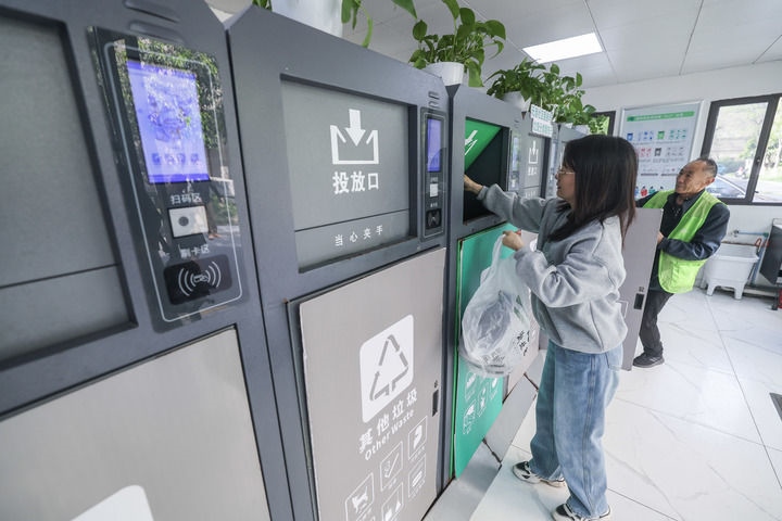 2024年4月10日，在浙江省湖州市吳興區(qū)飛英街道新華府小區(qū)內，居民在垃圾分類智能系統(tǒng)的指導下進行垃圾分類投放，居民的投放情況將實時匯總到智慧服務平臺，會有相應的積分獎勵。新華社記者 徐昱 攝