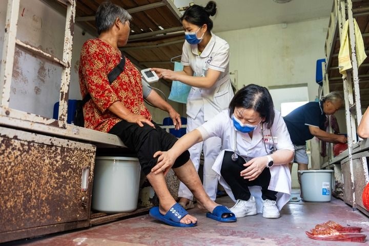 2024年7月30日，在湖南省湘潭縣河口中學(xué)安置點(diǎn)，醫(yī)務(wù)人員為受洪水影響而轉(zhuǎn)移安置的群眾檢查身體。 新華社記者 陳思汗 攝
