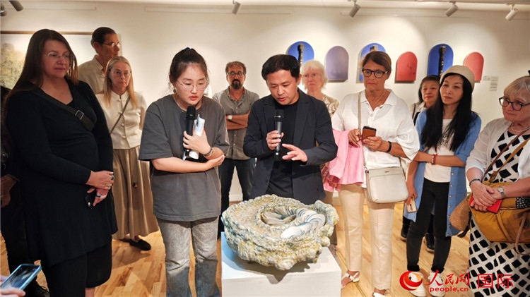 參展人、景德鎮(zhèn)陶瓷大學(xué)設(shè)計藝術(shù)學(xué)院副院長余劍峰（中）向來賓介紹參展作品。人民網(wǎng)記者 殷淼攝