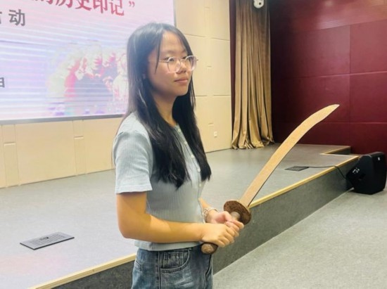 圖為南開大學社會實踐隊學生代表呼月紅在學術交流活動現場，展示河間調研行中獲贈的一戰(zhàn)華工蔡世春曾使用過的一把大刀。林卓瑋 攝