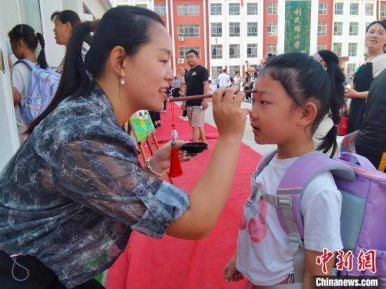 圖為衡水市利民路小學，老師為學生點朱砂痣，寓意開啟智慧。張松 攝