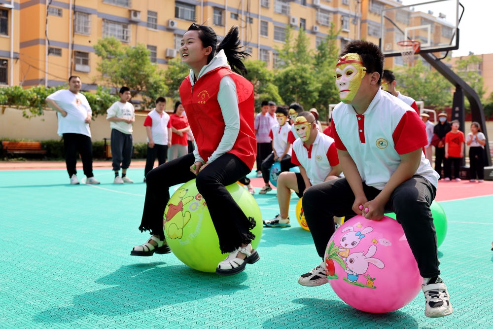 2024年5月17日，在山東省棗莊市市中區(qū)特殊教育中心，青年志愿者與智力障礙學(xué)生一起做游戲。新華社發(fā)（孫中喆攝）