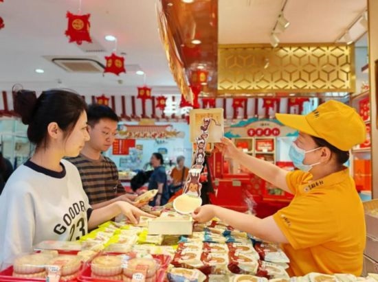 北京稻香村一家門店內(nèi)，售貨員向顧客展示新上市的月餅禮盒。（受訪者供圖）