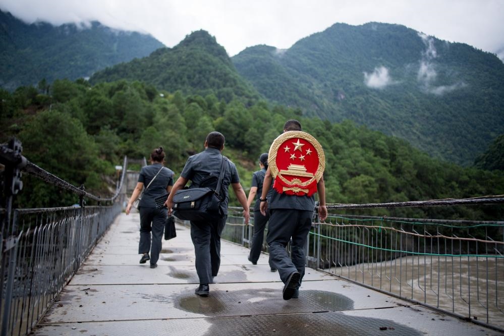 云南省怒江傈僳族自治州貢山縣人民法院法官鄧興背著國徽與同事們跨過怒江（2019年8月30日攝）。怒江高山峽谷眾多，交通不便，為方便群眾、更好地開展法律服務(wù)，背著國徽攀高山、過索橋、躲落石、鉆老林……成為鄧興法官的工作常態(tài)。新華社記者 江文耀 攝