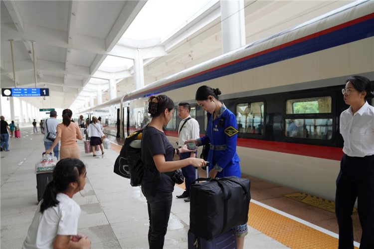 中老鐵路工作人員在站臺指引旅客進(jìn)站乘車。老中鐵路有限公司供圖