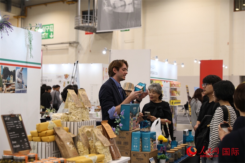 當(dāng)?shù)貢r間10月5日，在第21屆釜山國際美食博覽會上，意大利展商向參觀者們介紹的意大利食品。人民網(wǎng)記者 莽九晨攝
