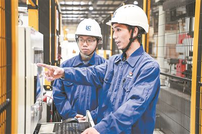在廣西柳工機(jī)械股份有限公司生產(chǎn)車間內(nèi)，一名高級技師（右）給徒弟講解數(shù)控設(shè)備操作細(xì)節(jié)。新華社記者 曹祎銘攝