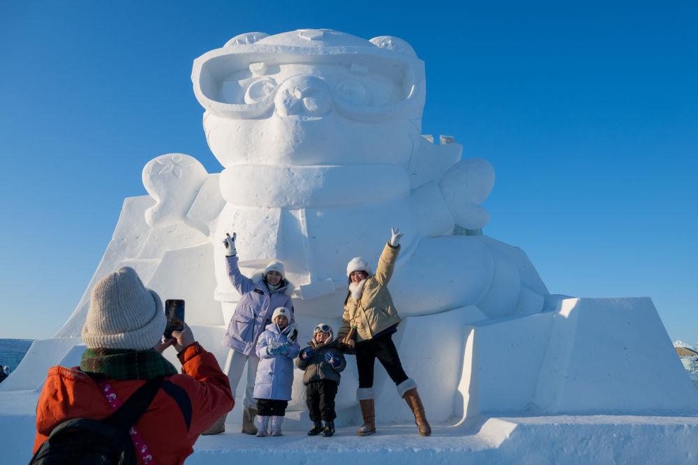2025年1月3日，在黑龍江哈爾濱冰雪大世界園區(qū)，游客與亞冬會(huì)吉祥物雪雕“濱濱”合影