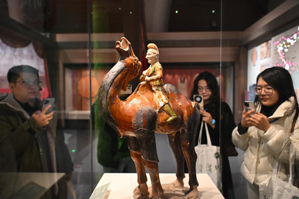 1月15日，觀眾在拍攝“長安三萬里——陜西唐代文物精華展”展出的三彩胡人騎駝俑。（新華社記者 孫凡越 攝）