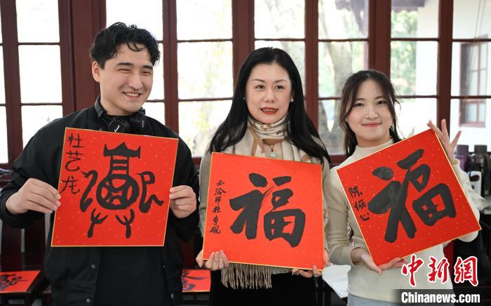 1月20日，外籍留學(xué)生和西泠印社社員李硯(中)展示各自創(chuàng)作的福貼。當日，來自巴西、馬來西亞、加納、哈薩克斯坦的外籍留學(xué)生在浙江杭州西泠印社體驗福貼、春聯(lián)和篆刻，感受古老的中國傳統(tǒng)文化。中新社記者 王剛 攝