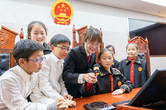 圖①：干警帶同學(xué)們體驗(yàn)敲法槌。