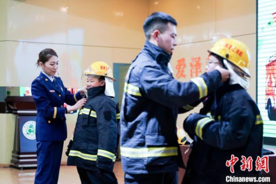 圖為學生們現(xiàn)場穿戴消防頭盔和戰(zhàn)斗服。中新社記者 趙宇航 攝