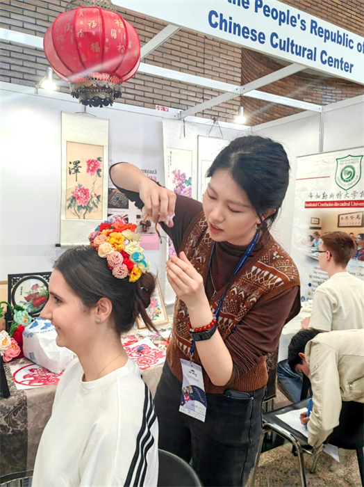 展覽正值羅馬尼亞迎春花節(jié)，國際中文教師志愿者潘婧穎向游客們介紹了國家非物質(zhì)文化遺產(chǎn)——福建泉州的簪花文化。布加勒斯特大學(xué)孔子學(xué)院供圖。