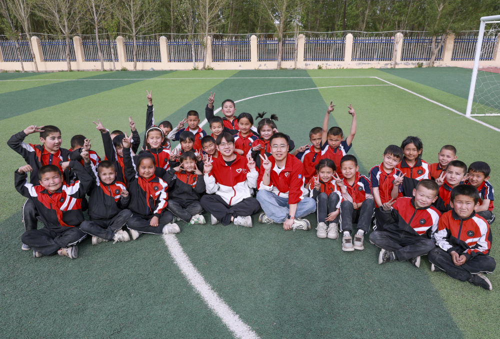 4月23日，在新疆克州阿圖什市哈拉峻鄉(xiāng)謝依特小學(xué)，支教教師王俊文（中左）、李軻凡（中右）和學(xué)生在一起。